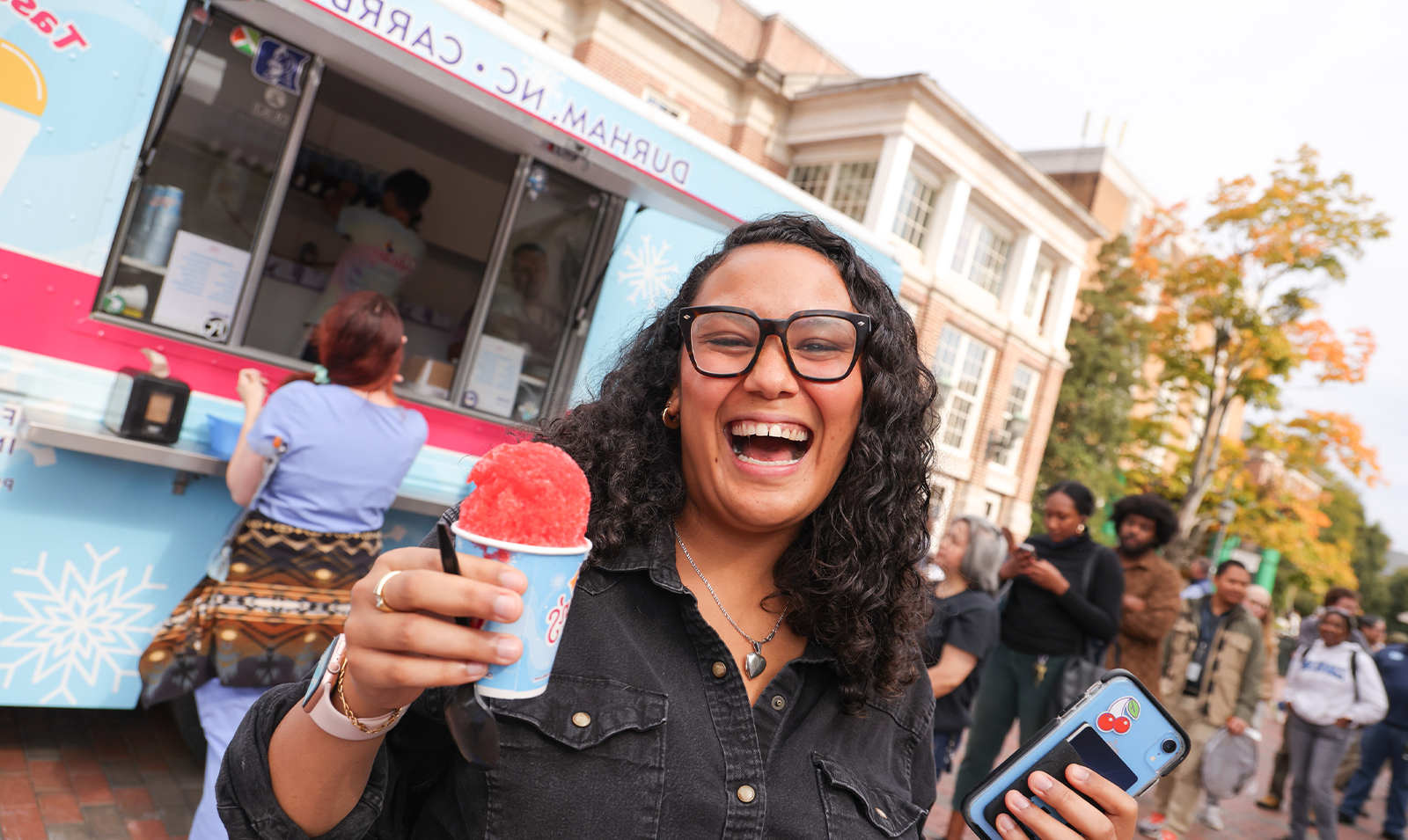 A woman smiling and holding a snowcone.